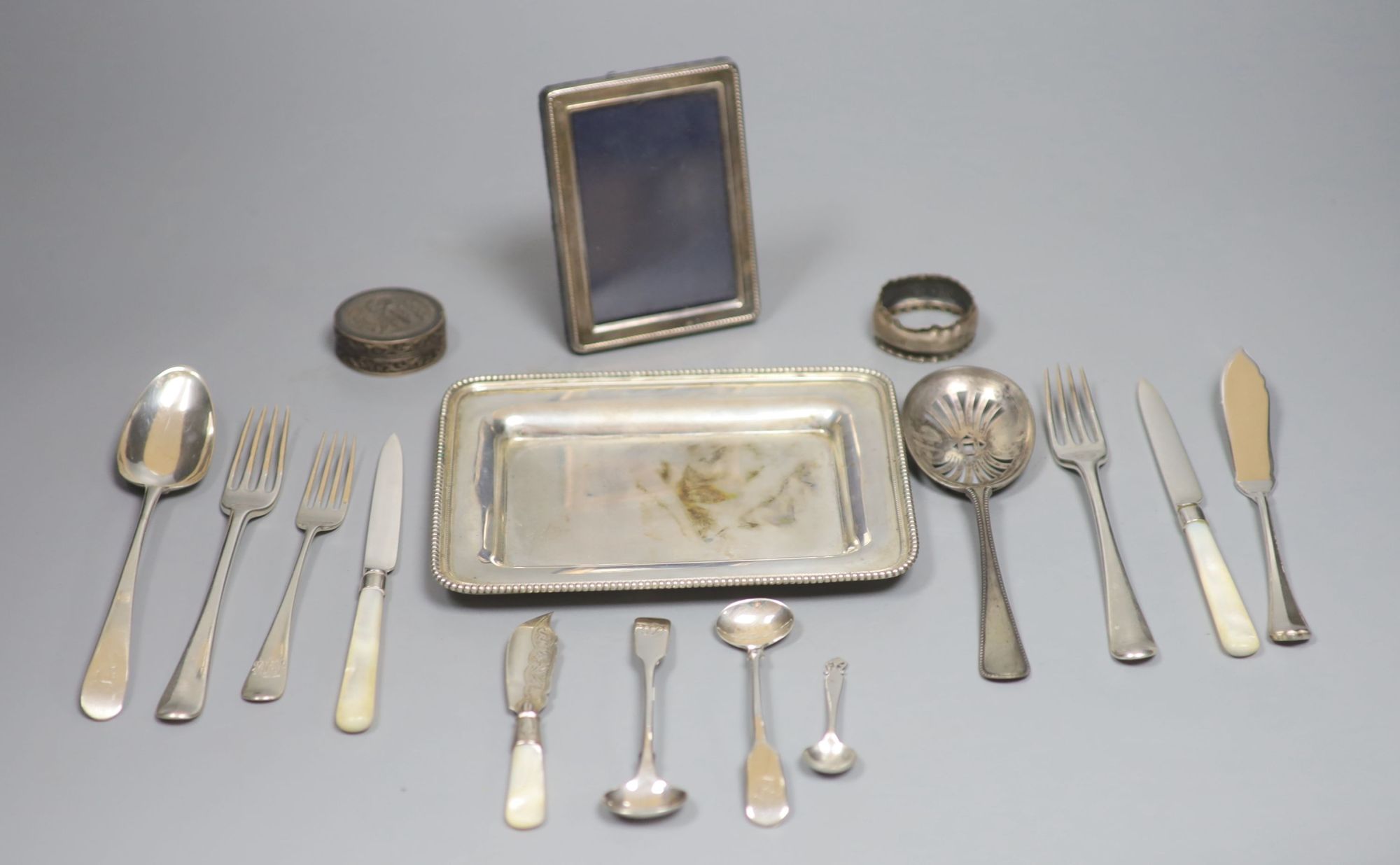 An 800 white metal stand, 16.4cm, twelve items of assorted silver flatware, a silver napkin ring, frame and box.